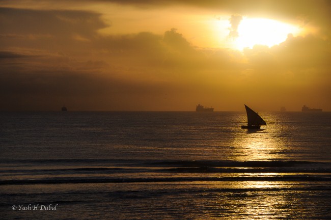 Sunrise at the sea with sail boat floating over the horizon - free high resolution image
