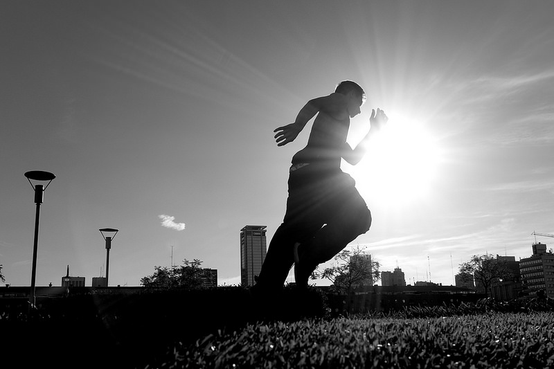 Black and white image of a boy running on a sunny day